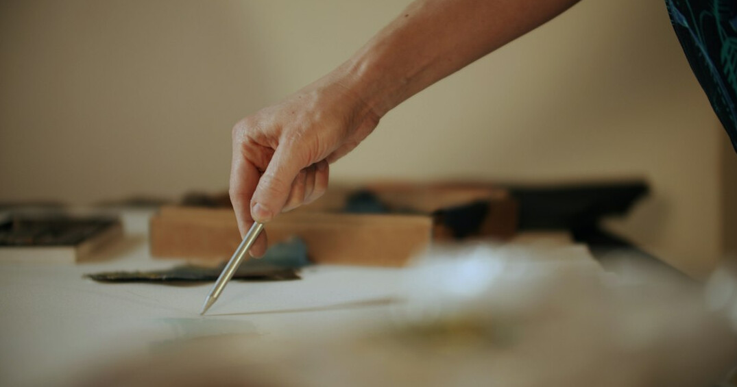 Hands writing notes with a pen over documents